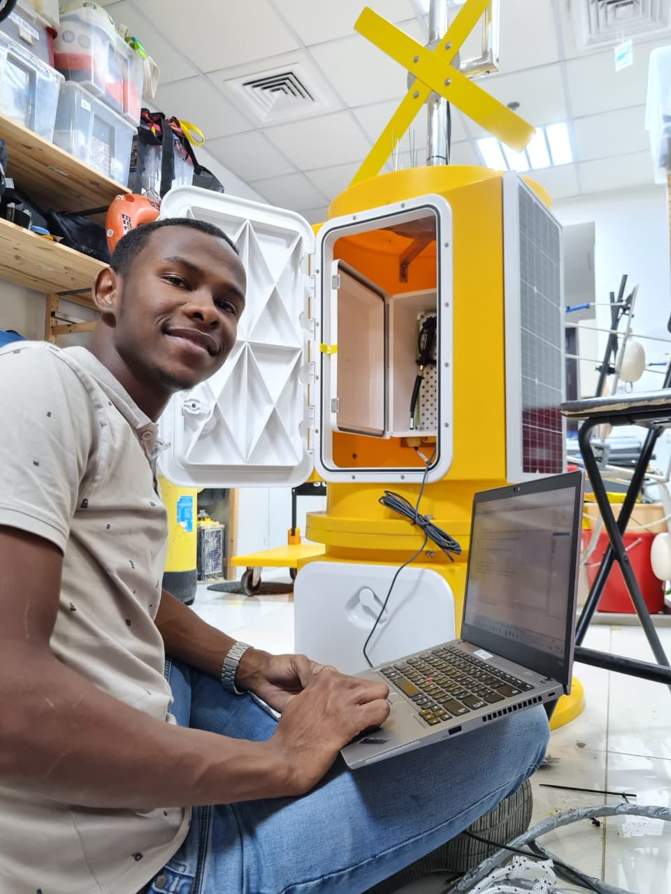 Husam configuring a monitoring buoy with a laptop in a workshop