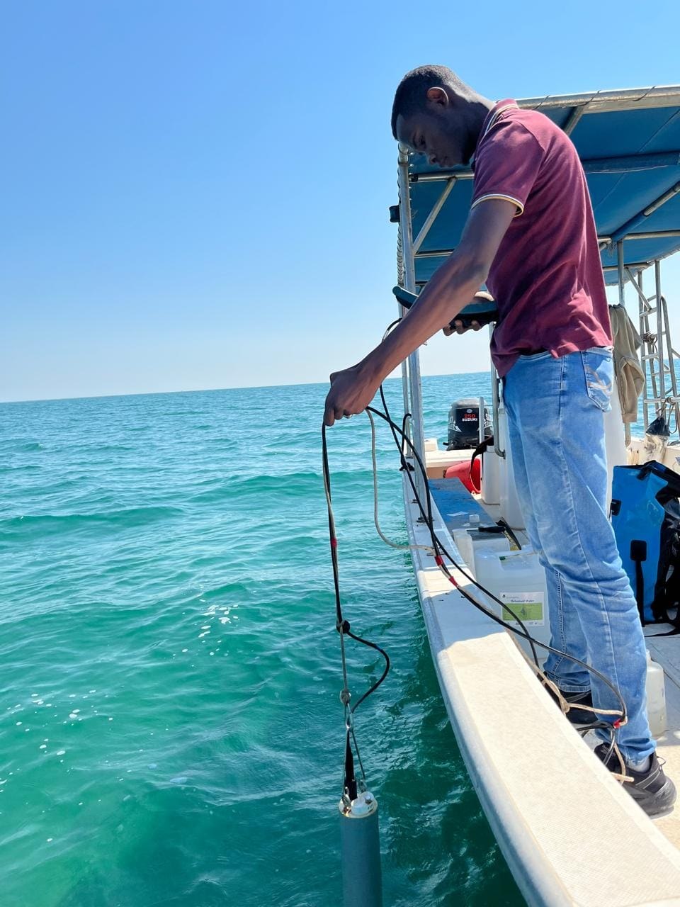 Husam lowering a water-quality instrument from a boat during marine fieldwork