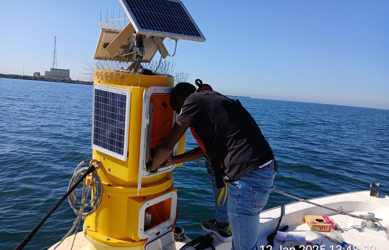 Husam servicing an open offshore monitoring station from a boat